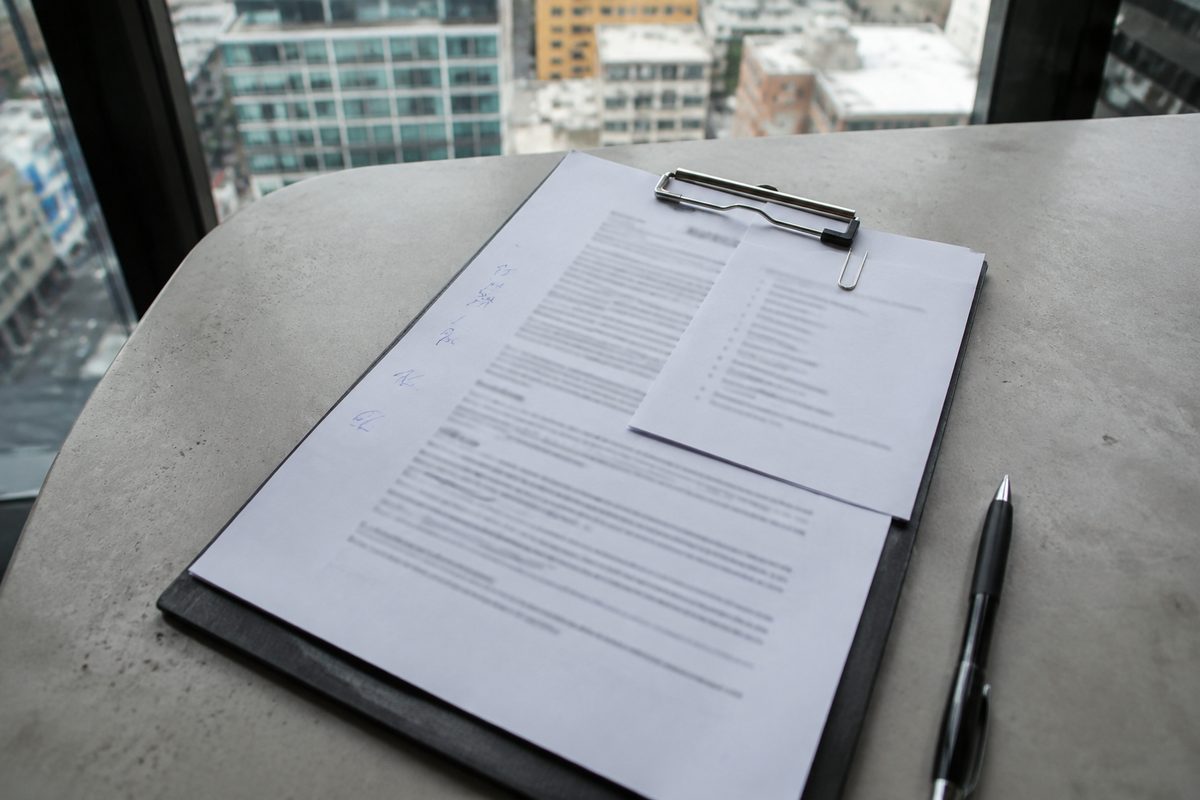 A printed engagement letter with margin initials on a clipboard
